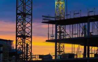 Steady Cash Flow: Image of a construction site at dusk with orange and purple hues in the sky. Scaffolding from Dale Scaffolding is visible in the background.