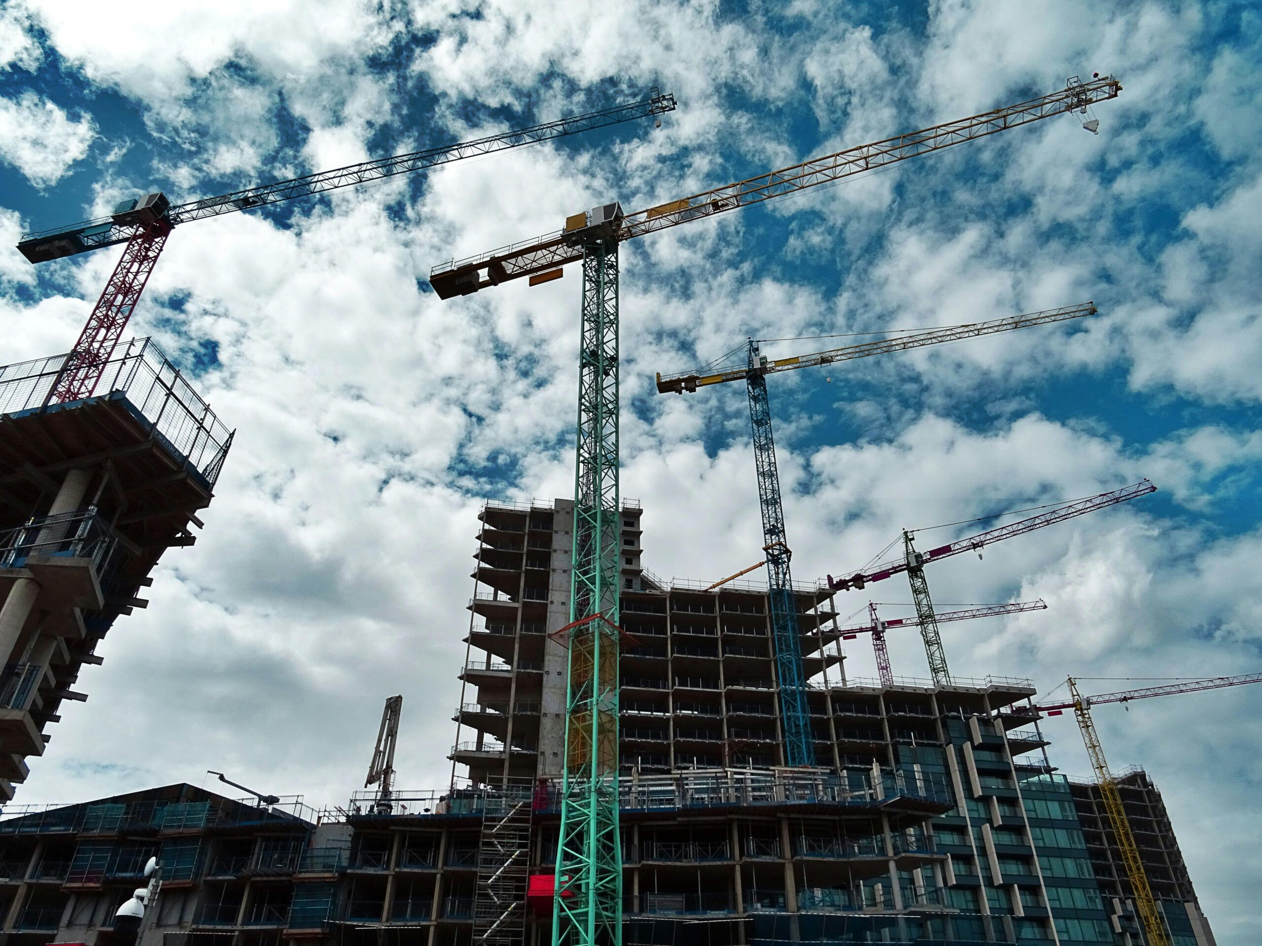A photo of a high-rise building under construction with multiple cranes in the sky.