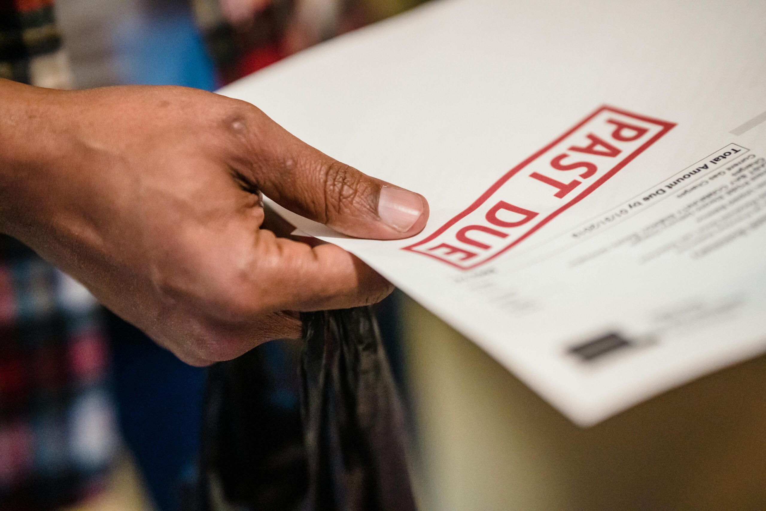 erson holding overdue payment notice, highlighting debt collection.