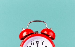 Get Paid Faster! Red twin bell alarm clock with black face showing 11:12 sits on a blue background.