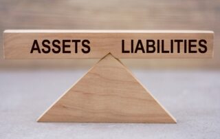 Wooden block divided into "Assets" and "Liabilities" sections, illustrating an Asset and Liability Report used in debt collection.