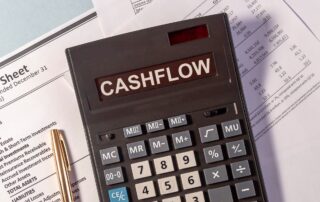 Cash Flow Tips: Calculator showing the word "cashflow" on top of a financial statement. Text on the statement includes "Income," "Expenses," "Liabilities," and "Assets." This image is used in a blog post about cash flow management tips for businesses.