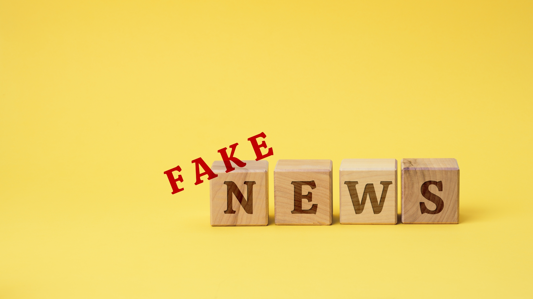 Debunking Common Misconceptions: Wooden blocks with the text "fake news" on a yellow background. Debt collection myths debunked.