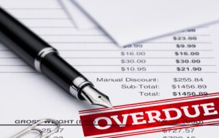 Close-up of a fountain pen resting on top of an invoice with a red "Overdue" stamp.