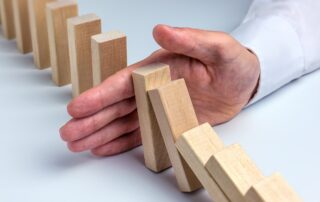 Hand stopping dominoes representing bad debt prevention
