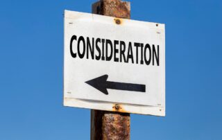 A close-up photo of a rectangular white sign with blue text that says "consideration" with a leftward blue arrow.