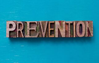 Cash Flow Tips: Wooden letterpress spelling the word "prevention" in capital letters. The blocks sit on a flat blue background. This image is used in a blog post about cash flow management tips for businesses.