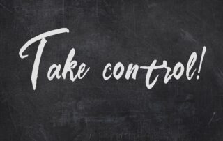 Managing Business Stress: Text on a blackboard reading "Take Control" in white chalk. This is a motivational message encouraging business owners to take charge of their finances during uncertain times.