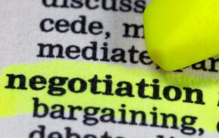 Navigating Debt Negotiation: Image of a dictionary open to a page with the word "negotiation" highlighted in yellow marker. Text around the highlighted word includes "cede," "mediate," "bargaining," and "concede." This image represents planning and research for debt negotiation.