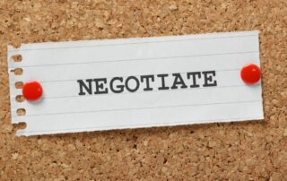 Negotiate Debt Settlements: Image of a piece of paper pinned to a corkboard with the word "Negotiate" written on it in black ink. Debt settlement concept.