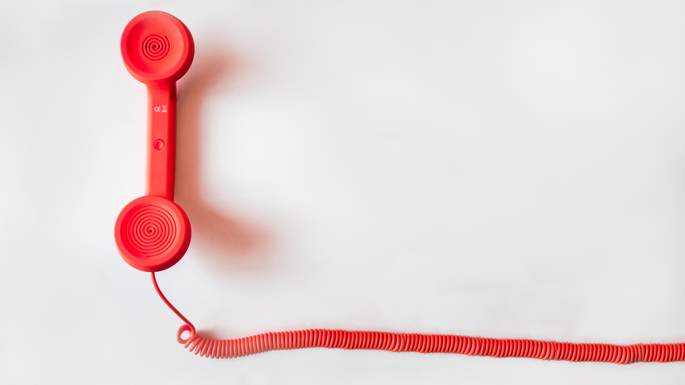 Beyond Phone Call: A red phone on a white background, symbolizing traditional communication methods in debt collection.