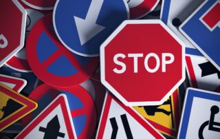 Debt Collection Scams Targeting Businesses: A STOP sign amidst various road signs, representing the importance of recognizing and stopping debt collection scams.