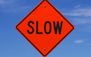 A "SLOW" road sign representing the negative impact of late payments on business cash flow.