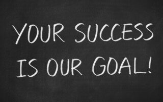 International Debt Recovery Solutions: Handwritten chalk message on a blackboard: "Your success is our goal!" (The Baker Group's commitment to client success in debt recovery).